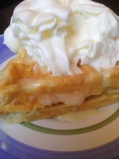 a waffle topped with whipped cream on top of a blue and green striped plate