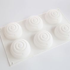 four white cupcakes sitting on top of a plastic tray next to each other