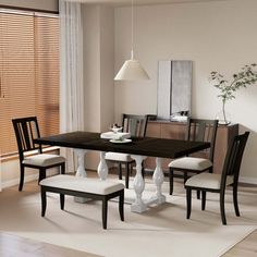 a dinning room table with four chairs and a bench in front of the window