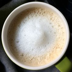 a cup filled with liquid sitting on top of a green and white towel next to a spoon