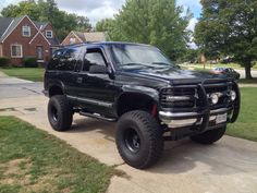 a large black truck parked in front of a house