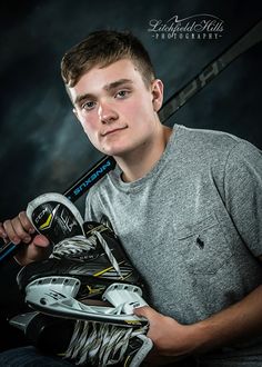 a young man is holding his hockey equipment