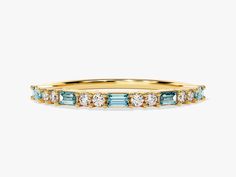 a yellow gold band with blue and white stones on the sides, set against a plain background