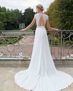 a woman in a white wedding dress standing on a balcony with her back to the camera