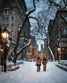 two people walking down a snow covered street