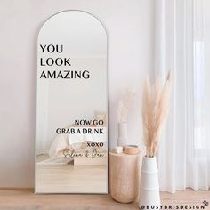 a mirror sitting on top of a wooden floor next to vases and plants in front of a window