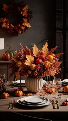 a table set with plates, silverware and autumn leaves in a vase on it