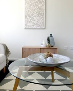 a living room with a glass coffee table and white couches in the back ground