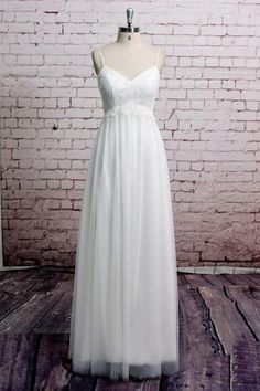 a white wedding dress on a mannequin stand in front of a brick wall