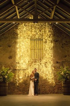 a couple standing in front of a wall with lights on it