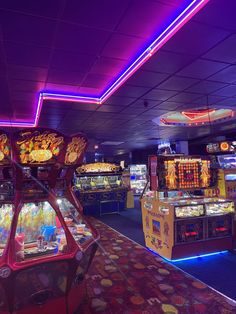 an arcade game room with neon lights and games on the walls, along with other machines