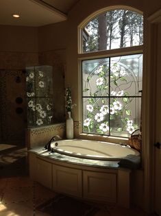 a bath tub sitting next to a window with flowers on the glass in front of it