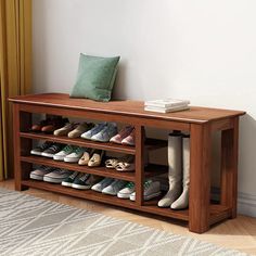 a wooden bench with shoes on it and a green pillow sitting on top of it