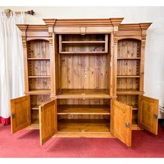 a large wooden cabinet with doors open on the side and shelves below it, in a room with red carpeted flooring