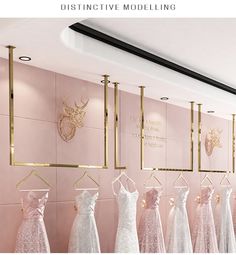 there are many dresses on display in the store with gold trimmings and pink walls