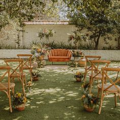 an outdoor seating area with wooden chairs and potted plants on the lawn, surrounded by trees