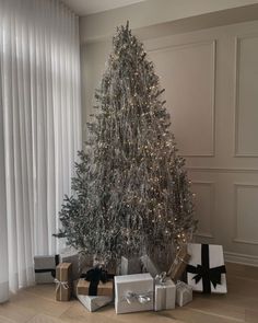 a silver christmas tree with presents under it