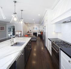 a kitchen with white cabinets and marble counter tops, along with dark wood flooring