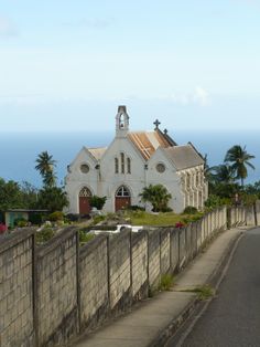 an old church sits on the side of a road next to a large body of water