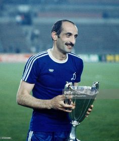 a man holding a trophy on top of a soccer field