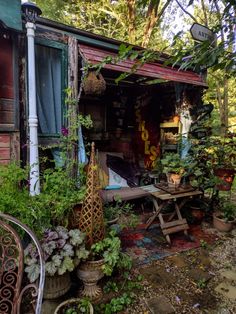 an old shed is covered in plants and potted plants on the outside, along with other outdoor furniture