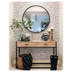 a black and white wall with a round mirror on top of it next to a wooden table