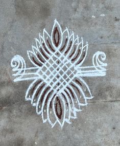 an intricately designed design on the ground in white and brown colors is drawn with chalk