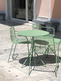 a green table and chairs sitting on the sidewalk