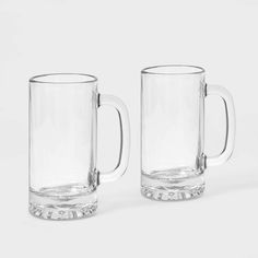 two clear glass mugs sitting next to each other on a white surface, one is empty