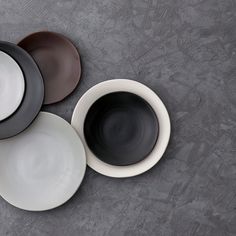 four black and white plates sitting next to each other on top of a gray surface