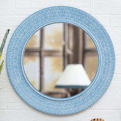 a blue mirror sitting on top of a wall next to a table with a lamp