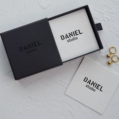 an open box with two gold rings on top of it next to a pair of earrings