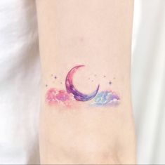 a woman's arm with a watercolor crescent tattoo on the left side of her body