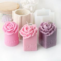 three candles with pink and purple flowers on them