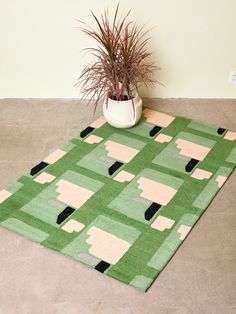 a green rug with black and pink shapes on it next to a potted plant