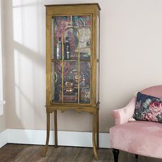 a pink chair sitting next to a tall wooden cabinet with glass doors on it's sides