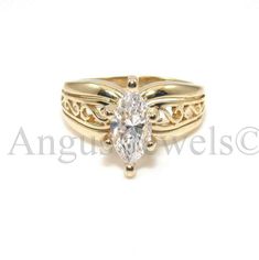 a yellow gold ring with an oval cut diamond in the center and filigrees on