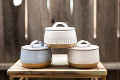 three white and blue pots sitting on top of a wooden table