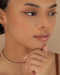 a woman wearing a necklace with a nose ring on her left hand and an earring on her right