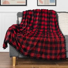 a red and black plaid blanket sitting on top of a couch next to two pictures