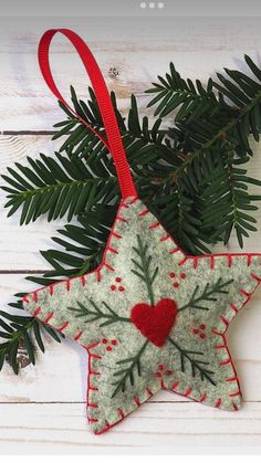 an ornament hanging from a tree branch with a red heart in the center