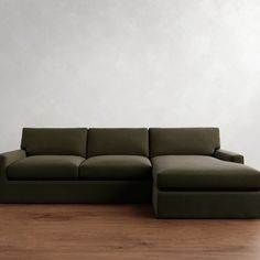 a green couch sitting on top of a hard wood floor next to a white wall