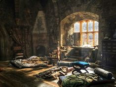 a room filled with lots of furniture next to a fire place in a stone building