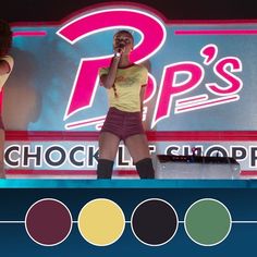 two women are performing on stage in front of a neon sign and color swatches