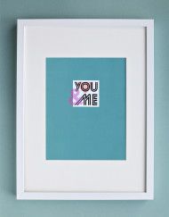 a white frame hanging on a wall with a blue background and the words you me