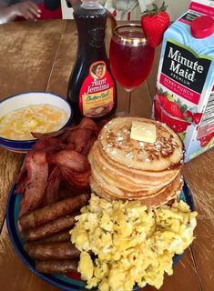 a breakfast plate with eggs, pancakes, sausages and fruit on the table next to milk