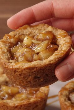 a hand is holding some food in the middle of two muffins on a plate