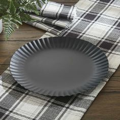 a black plate sitting on top of a wooden table next to a potted plant