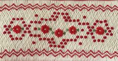 a red and white piece of cloth with flowers on the side, embroidered onto it