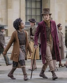 several people dressed in period clothing walking on the street